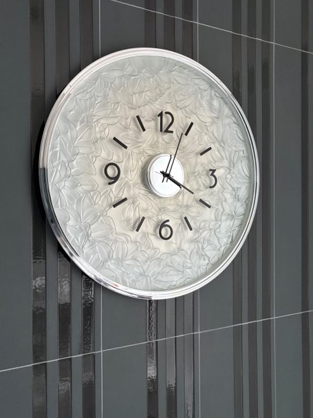 Horloge murale ronde avec aiguille des heures et des minutes sur fond gris.