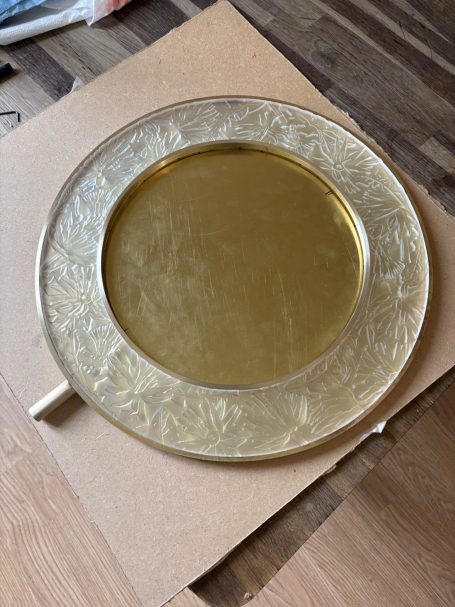 Assiette ronde dorée avec une texture délicate sur le bord.