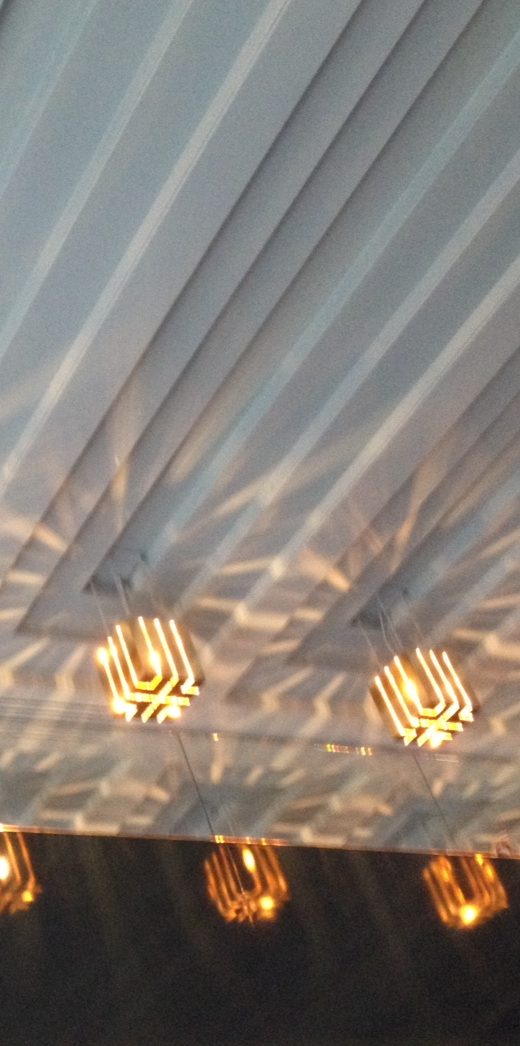 Lumières suspendues créant des reflets sur un plafond ondulé. 