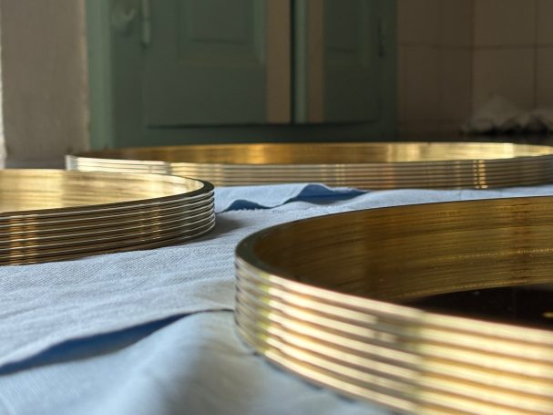Trois cercles en métal doré posés sur un tissu bleu.
