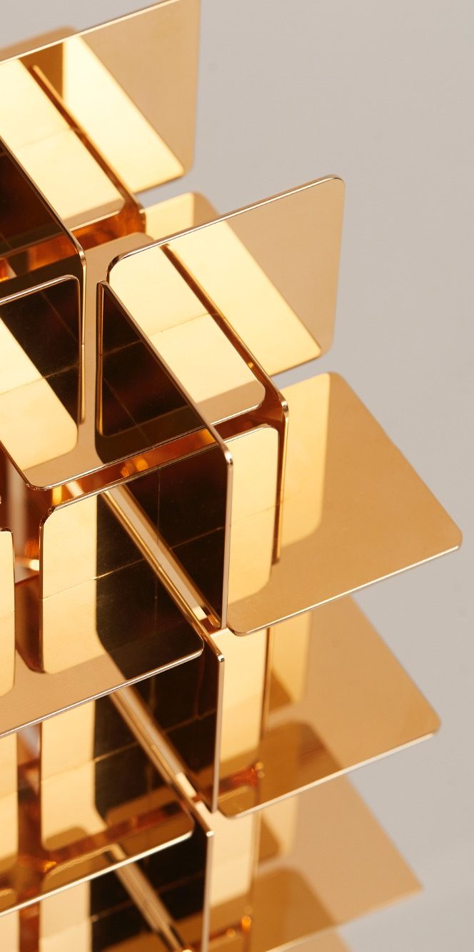 Structure de blocs de laiton dorés encastrés, créant un motif géométrique.