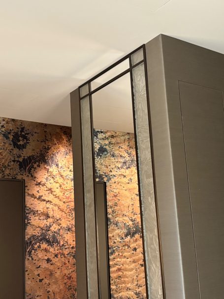 Détail d'un mur avec des motifs muraux et un miroir encadré élégant.
