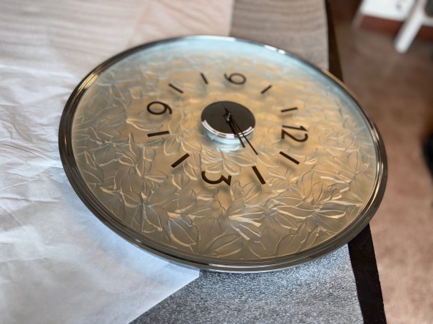 Montre à cadran argenté avec chiffres noirs, posée sur une surface claire.
