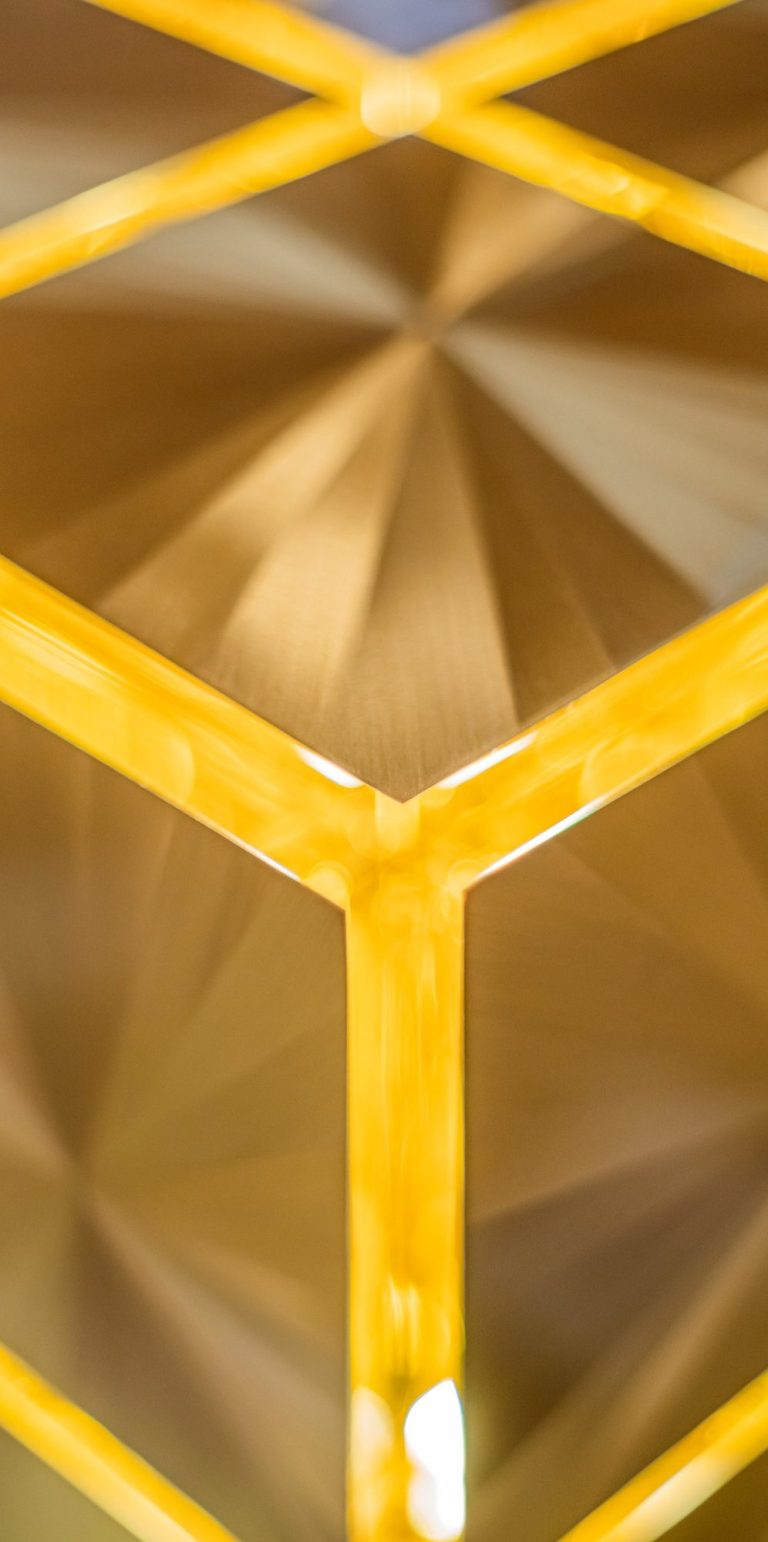 Structure de blocs de laiton dorés encastrés, créant un motif géométrique.