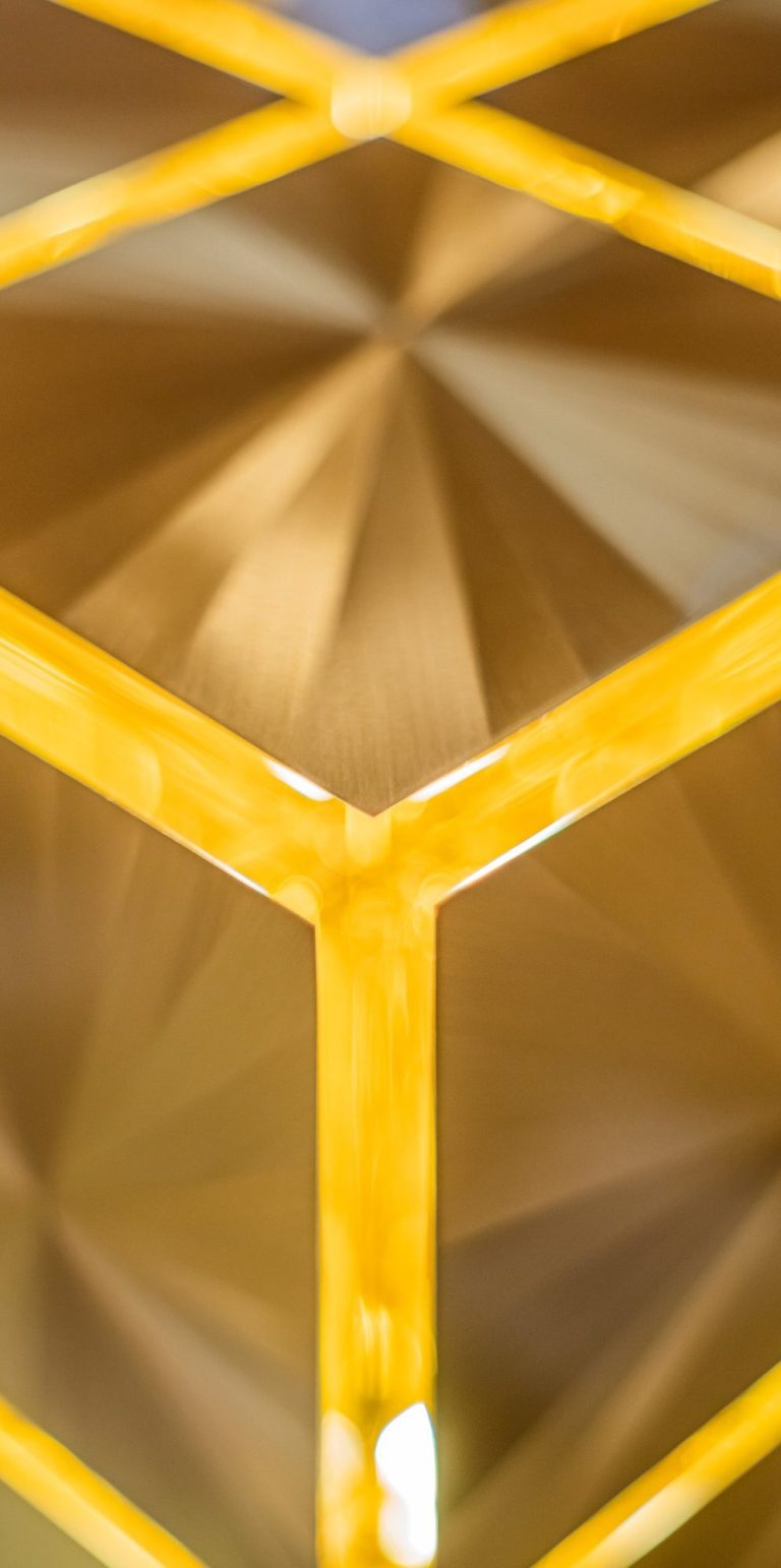 Structure de blocs de laiton dorés encastrés, créant un motif géométrique.