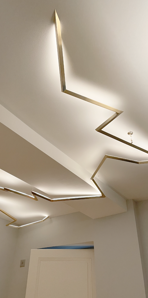 Luminaire suspendu en forme d'éclair, mur blanc.