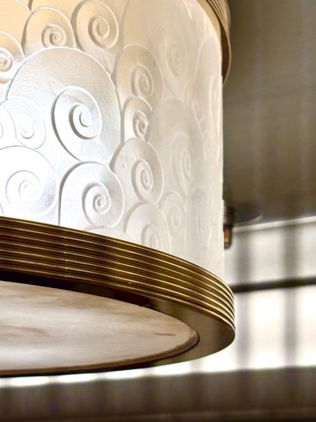 Plafonnier élégant avec détails en spirale et contours dorés.