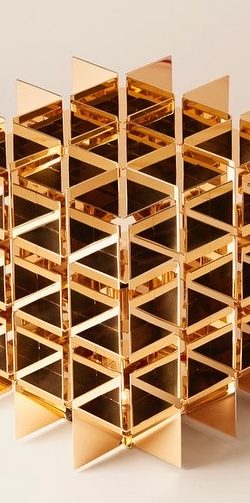 Structure géométrique en métal doré avec des motifs en cubes.