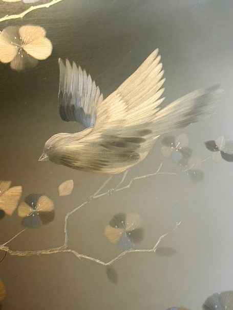 Un oiseau volant près de branches avec des fleurs dorées et une ambiance douce.