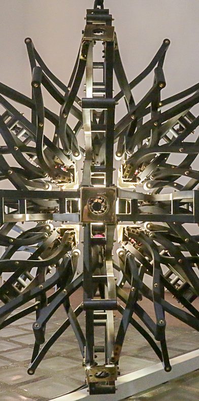 Suspension lumineuse en forme géométrique avec des lignes argentées et des lumières blanches.