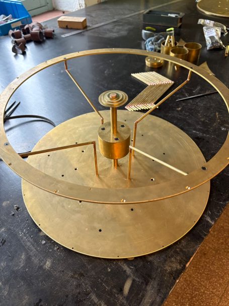Appareil en laiton avec un cadran circulaire et des composants mécaniques visibles.